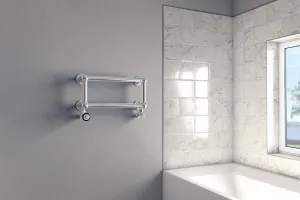 A small wall-hung Elara towel rail with two chrome bars and valves on a grey wall beside a white bath and marble-tiled window recess.