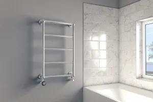 Wall-hung Elara towel rail in chrome with five horizontal bars and angled valves, on a grey wall beside a marble-tiled bath and window.