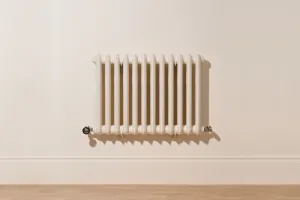 Wall-hung Emmeline II 670mm cast iron radiator in Farrow & Ball Dimity No. 2008 with Satin Nickel valves, above a skirting board and wooden floor.