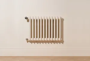 Wall-hung Emmeline II cast iron radiator in Farrow & Ball Dimity No. 2008 with Satin Nickel valves, on a cream wall above a wooden floor.