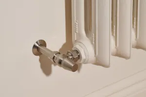 Close-up of an Emmeline II cast iron radiator in Farrow & Ball Dimity No. 2008 with a Satin Nickel angled valve and wall pipe cover.