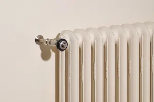 Close-up of an Emmeline II cast iron radiator in Farrow & Ball Dimity No. 2008, with a Satin Nickel valve against a cream wall.