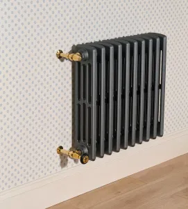 Plain wall-hung Grace 4 Column 660mm cast iron radiator in dark grey with brass valves, against star-patterned wallpaper above a wooden floor.