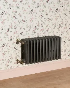Wall-hung Grace 6 Column 485mm cast iron radiator in Quartz Grey with Chatsworth valves in Natural Brass, below bird-print wallpaper.