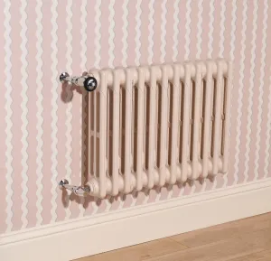 Wall-hung Mercury 3 Column 560mm cast iron radiator in Farrow & Ball Scallop No. 311 with chrome valves, on pink wavy-striped wallpaper.