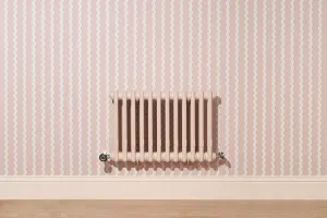 Wall-hung plain Mercury 3 column cast iron radiator in Farrow & Ball Scallop No. 311 with chrome valves, on pink wavy-striped wallpaper.