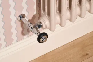 Close-up of a Mercury 3 Column cast iron radiator in Farrow & Ball Scallop No. 311 with a chrome angled valve, above a skirting board and oak floor.