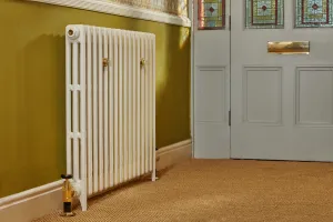 Mercury 3 Column 860mm cast iron radiator in Farrow & Ball Lime White No. 1 on feet with a brass angled valve, beside a stained-glass front door.
