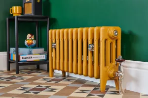 Low plain Mercury four-column cast iron radiator in mustard yellow on feet, chrome Windsor valve, green wall and patterned tiled floor.