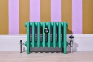 Low Mercury cast iron radiator in green Little Greene Woodland on feet, chrome valves, against lilac and mustard striped wallpaper.