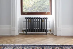 Plain Mercury 4 column cast iron radiator in Astral Grey Mid on feet with brass valves and stays, under a window on a herringbone floor.