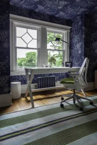 A plain Mercury 4 Column 460mm cast iron radiator in Caspian, wall-hung under a sash window behind a white desk in a blue floral study.