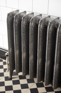 Ornate Rococo II 760mm cast iron radiator on feet in Etch-Coated Polish, with a nickel valve, white wall tiles and a black and cream chequered floor.