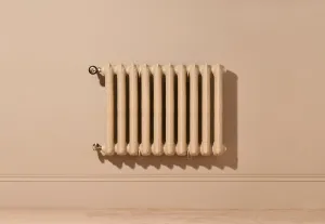 Ornate ten-section Rococo II cast iron radiator in Farrow & Ball Planter No. G5, wall-hung with brass valves above a skirting board.