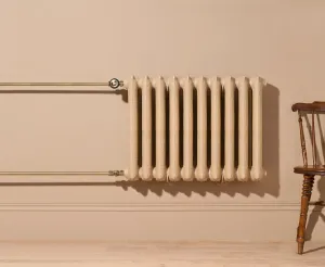 Ornate Rococo II 660mm cast iron radiator in Farrow & Ball Planter No. G5, wall-hung with brass pipes and valves beside a wooden chair.