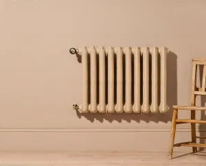 Ornate Rococo II cast iron radiator in Farrow & Ball Planter No. G5, wall-hung with angled valves, beside a wooden chair on a pale floor.
