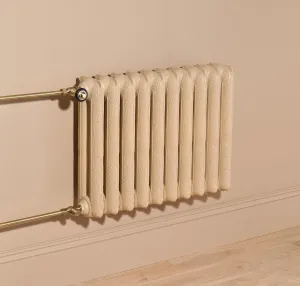 Ornate wall-hung Rococo II 660mm cast iron radiator in Farrow & Ball Planter No. G5 with brass valves and pipes above a pale wood floor.