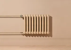 Ornate Rococo II cast iron radiator in Farrow & Ball Planter No. G5, wall-hung with brass pipes and valves above a skirting board.