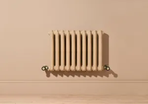 Ornate ten-section Rococo II cast iron radiator in Farrow & Ball Planter No. G5, wall-hung with valves, on a pink-beige wall above oak floor.