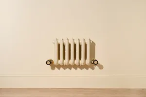 Ornate seven-column Rococo III 470mm radiator in Farrow & Ball Matchstick, wall-hung above a skirting board, with Natural Brass valves.