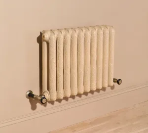 Ornate wall-hung Rococo II 660mm cast iron radiator in Farrow & Ball Planter No. G5 with brass angled valves, above a skirting board and wooden floor.