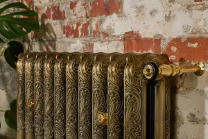 ornate cast iron radiator mounted on wall with cast iron brackets