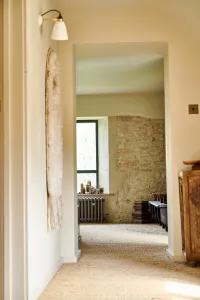View along a sisal-carpeted landing to a Grace 4 Column cast iron radiator in Grey Bronze below a window beside a stone wall.