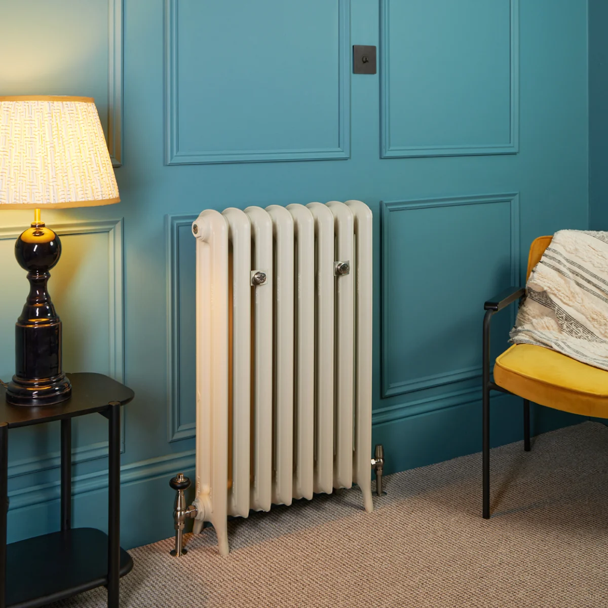 Emmeline II 870mm cast iron radiator in Portland Stone on feet, with Satin Nickel Windsor valves and stays, against a teal panelled wall.