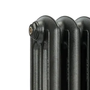 Close-up of the top corner of an Emmeline III cast iron radiator in a dark graphite finish, showing rounded columns and a brass bleed plug.