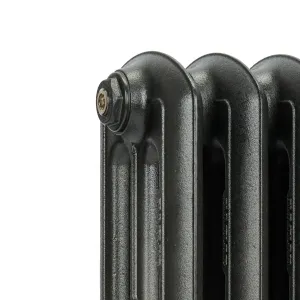 Close-up of the top corner of an Emmeline III cast iron radiator in a textured dark grey finish, showing plain rounded columns and a brass bleed plug.