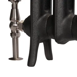Close-up of the foot of an Emmeline I cast iron radiator in Matt Black, with a brushed nickel angled valve and floor pipe shroud.
