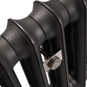 Close-up of an Emmeline I cast iron radiator in Matt Black, showing its curved columns and a brushed nickel wall stay between sections.