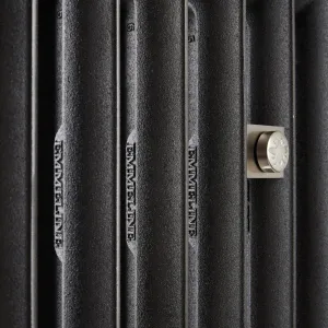 Close-up of Emmeline I cast iron radiator columns in a textured black finish, with EMMELINE cast lettering and a satin nickel wall stay.