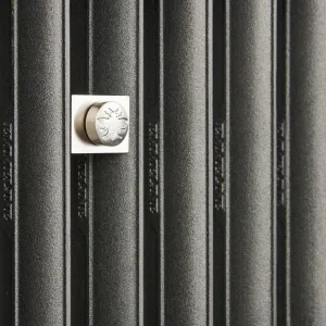 Close-up of Emmeline II cast iron radiator columns in Black Iron with embossed lettering and a nickel wall stay stamped with a bee.