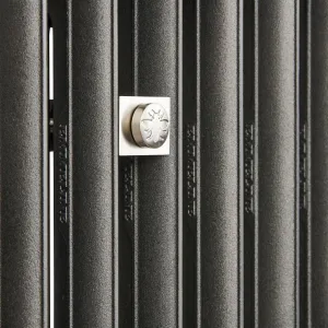 Close-up of Emmeline II cast iron radiator columns in Black Iron with a square polished nickel wall stay bearing an embossed bee.