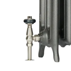 Close-up of the foot of an Emmeline III cast iron radiator in a textured dark grey finish with a satin nickel angled thermostatic valve.