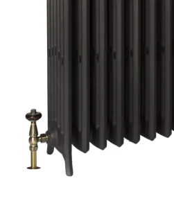 Close view of a Grace 6 column cast iron radiator in dark grey on feet, with an antique brass angled valve and wooden head, on white.