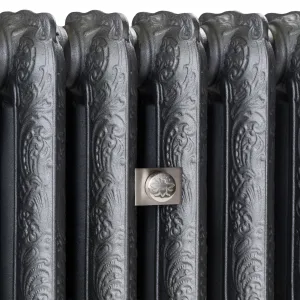 Close-up of ornate Rococo II cast iron radiator columns in Black Iron, with a brushed nickel square wall stay bearing a bee emblem.