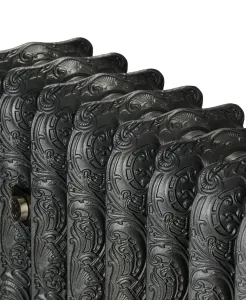 Close-up of the ornate scrolled top of a Rococo III cast iron radiator in a dark iron finish, with a satin nickel valve fitting.