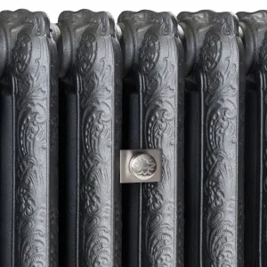 Close-up of ornate Rococo II cast iron radiator sections in Black Iron, with a brushed nickel bee-motif fitting on a square plate.