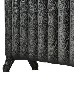 Close-up of an ornate Rococo II cast iron radiator with swirling scroll patterns on each section, dark iron finish, on scrolled feet.
