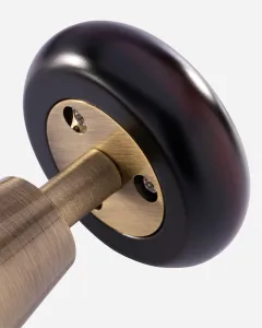 Close-up of a Windsor manual radiator valve in Antique Brass, showing the brass spindle and fixing screws inside a dark wooden-look handwheel.