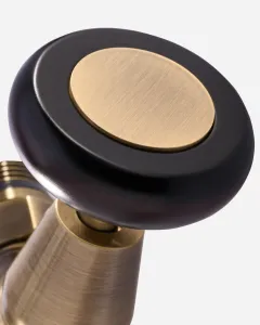 Close-up of a Windsor angled manual radiator valve in Antique Brass, with a dark wooden-look round head and brushed brass centre disc.