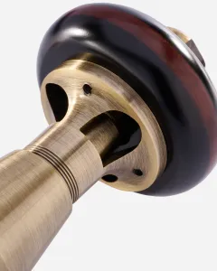 Close-up of a Windsor radiator valve in brushed Antique Brass, showing the ringed body and cut-away collar beneath a dark wooden head.