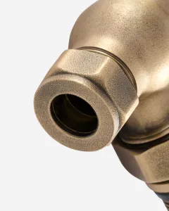 Close-up of the hexagonal compression nut and pipe inlet on a Windsor angled radiator valve in a textured Natural Brass finish.