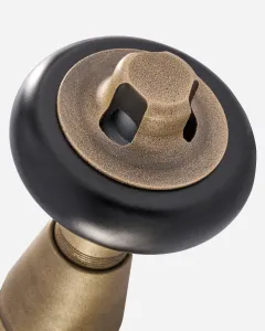 Close-up of a Windsor angled radiator valve head: a round black knob with a textured brass centre cap and square key socket, on a brass body.