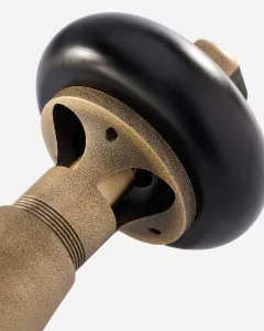 Close-up of a Windsor radiator valve in Natural Brass with a textured cast body, ribbed collar and black round head, on a white background.