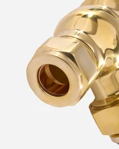 Close-up of a Windsor radiator valve in Unlacquered Brass, showing the hexagonal compression nut and open pipe inlet on a pale grey background.