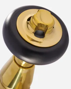 Close-up of a Windsor radiator valve in Unlacquered Brass, with a round black head and a brass centre cap on a brass body.