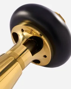 Close-up of a Windsor angled thermostatic radiator valve in unlacquered brass, showing the ribbed body, mounting flange and black round head.